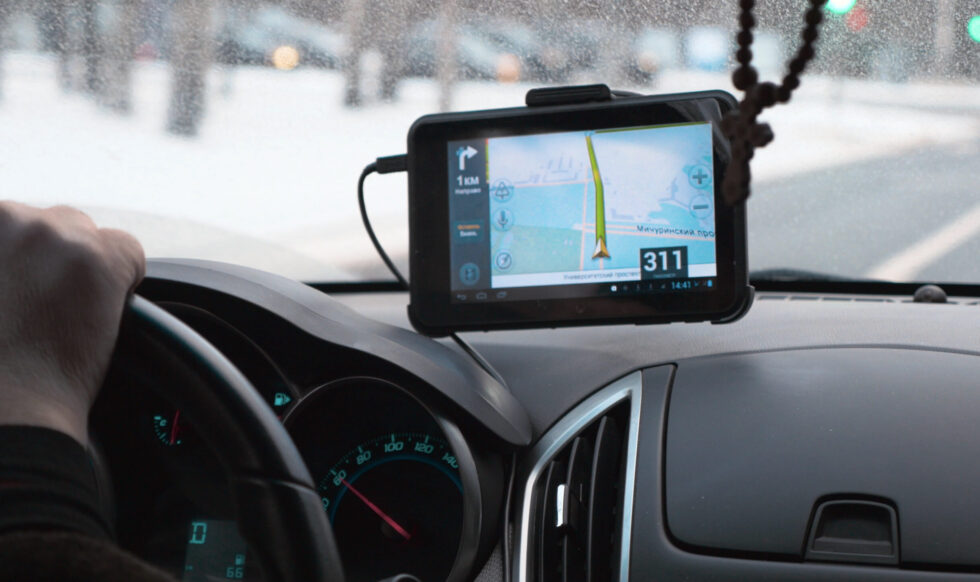 Driving a car with GPS device over dashboard Close-up shot of car driving with GPS device over the dashboard showing a route