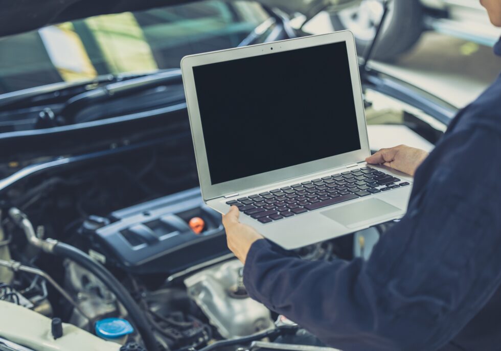 laptop computer blank screen with modern car engine performance ECU tune up in auto garage workshop