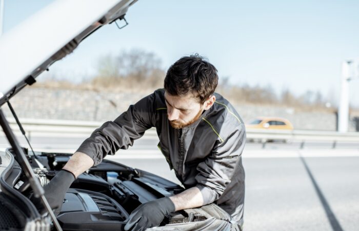 Auto mechanic repairing car outdoors