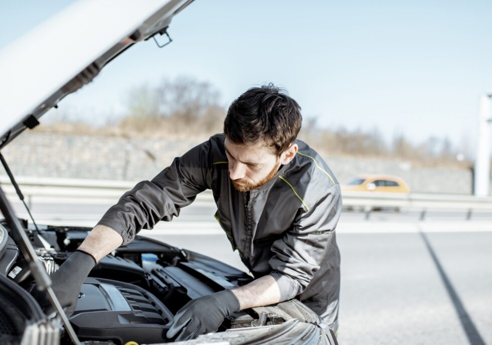 Auto mechanic repairing car outdoors